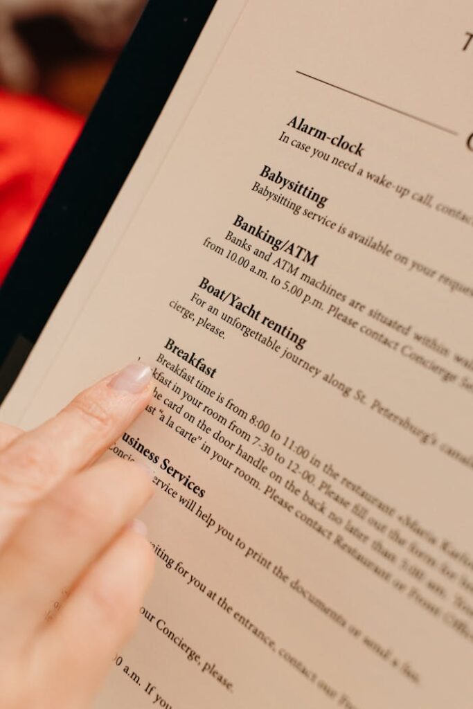 Close-up of a hand pointing at hotel service menu details on paper.